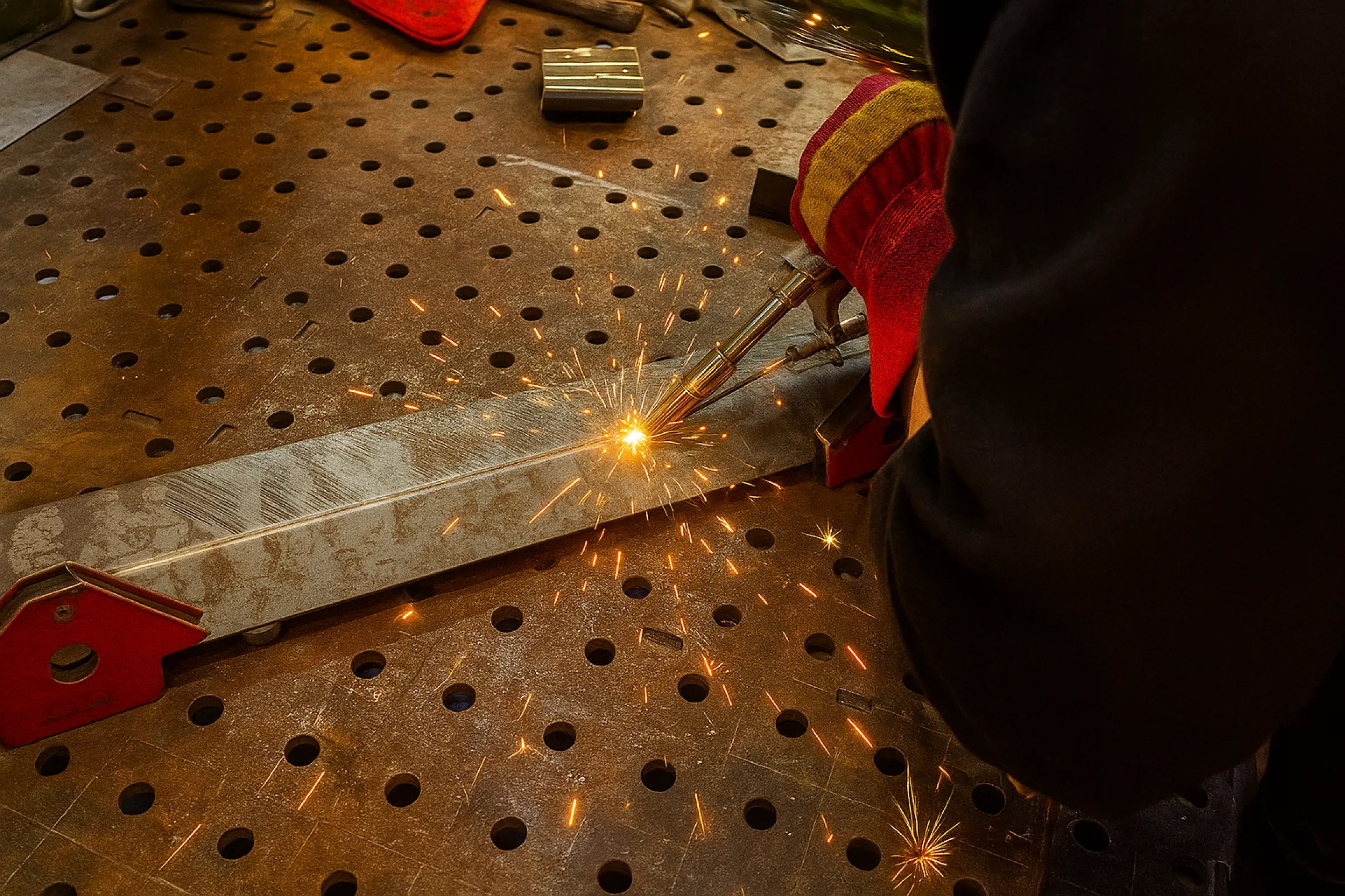 Процесс сварки металлических деталей на рабочем столе с вылетающими искрами