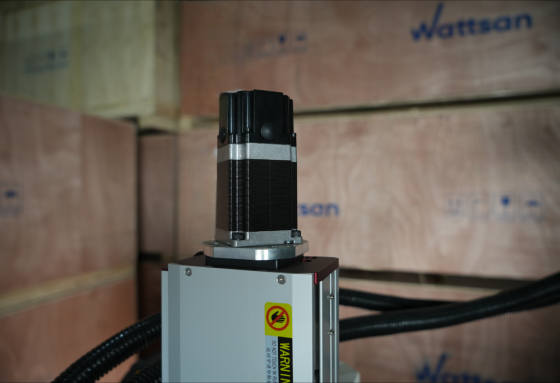 Шаговый двигатель черного цвета, закрепленный на верхней части вертикальной оси станка.