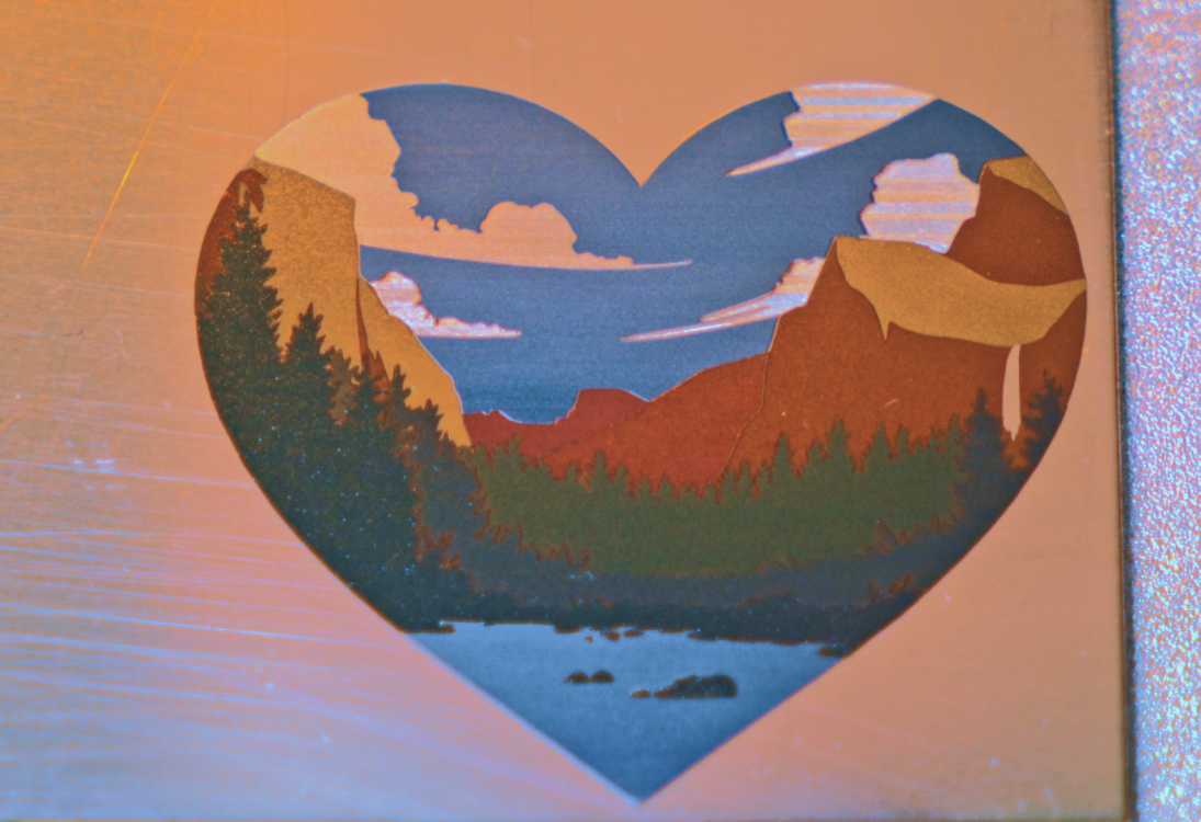 Сердцевидная гравировка пейзажа с горами, деревьями, озером и облаками в стиле Йосемити.